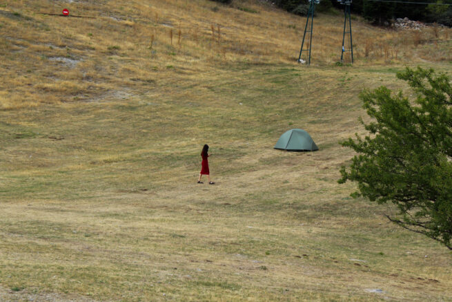 Nature. A person dressed in red and a green camping tent