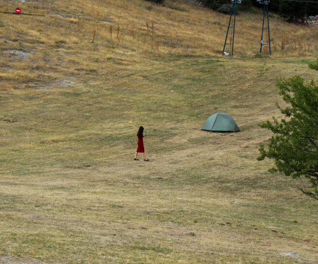 Nature. A person dressed in red and a green camping tent