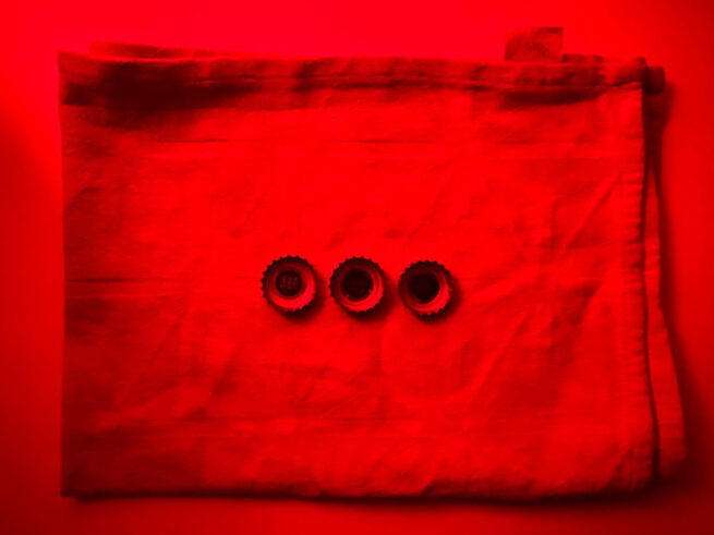 three bottle caps on a textile. The photograph has red colour