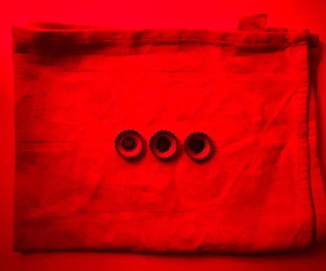 three bottle caps on a textile. The photograph has red colour