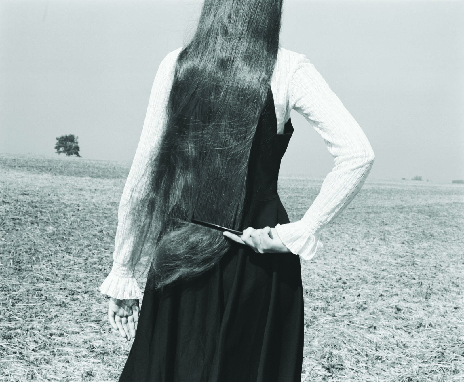 a back of a woman with long hair dressed with black dress