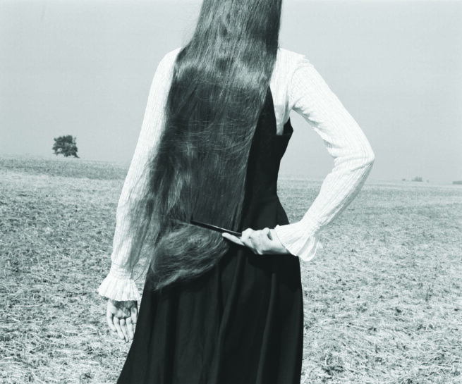 a back of a woman with long hair dressed with black dress