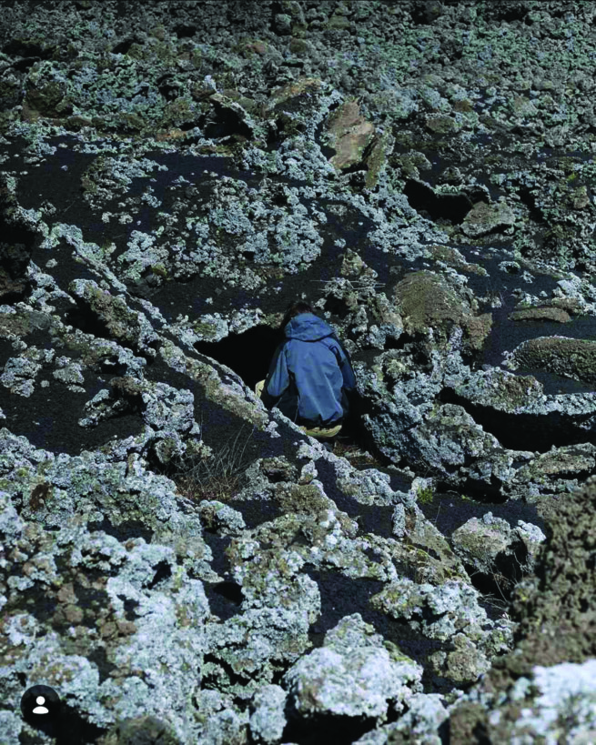 the back of a person sitting on the rocks