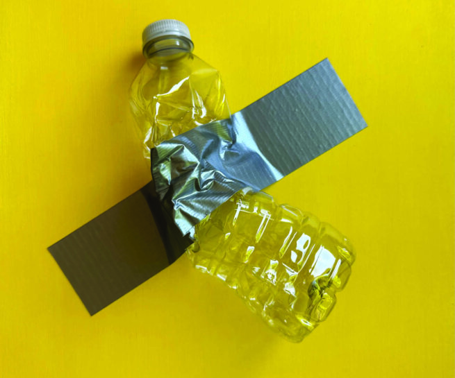 A water bottle taped with a grey gaffer tape on a yellow wall
