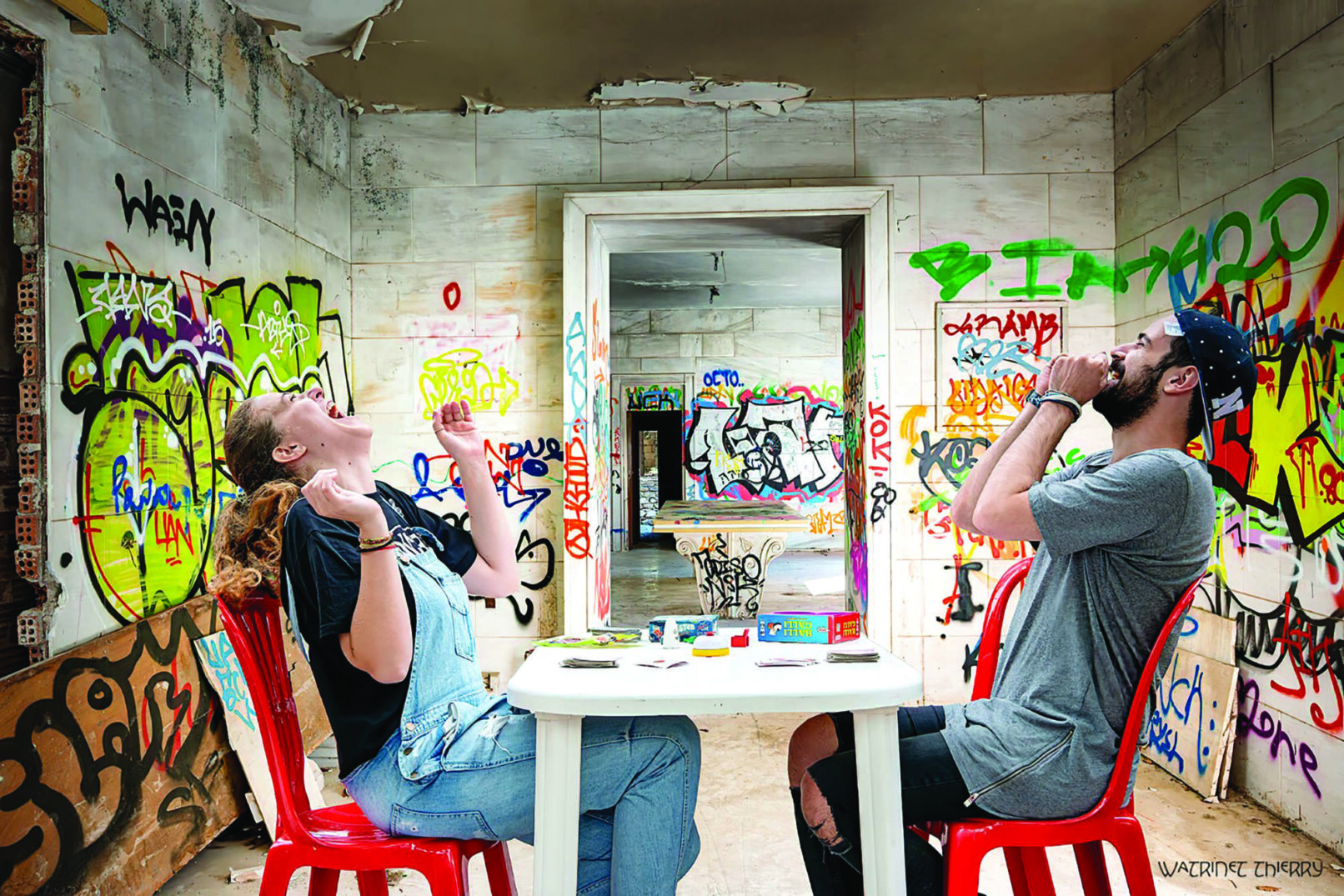 A woman and a man siting on red chairs and laughing