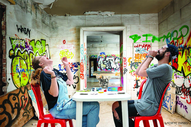 A woman and a man siting on red chairs and laughing