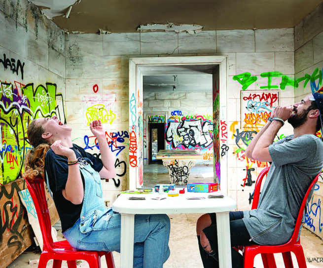 A woman and a man siting on red chairs and laughing