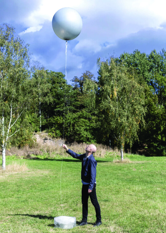 a person holding a grey ballon in the nature