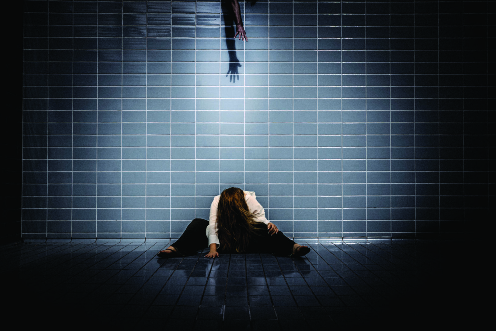 a woman sitting in front of a tiled wall